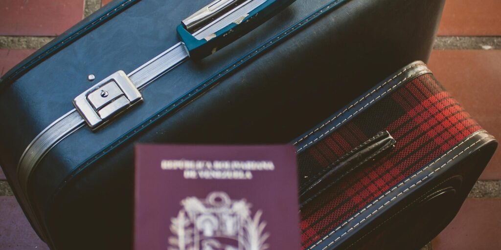 A traveler's essentials including a passport and suitcase on a red tiled floor, suggesting a journey ahead.