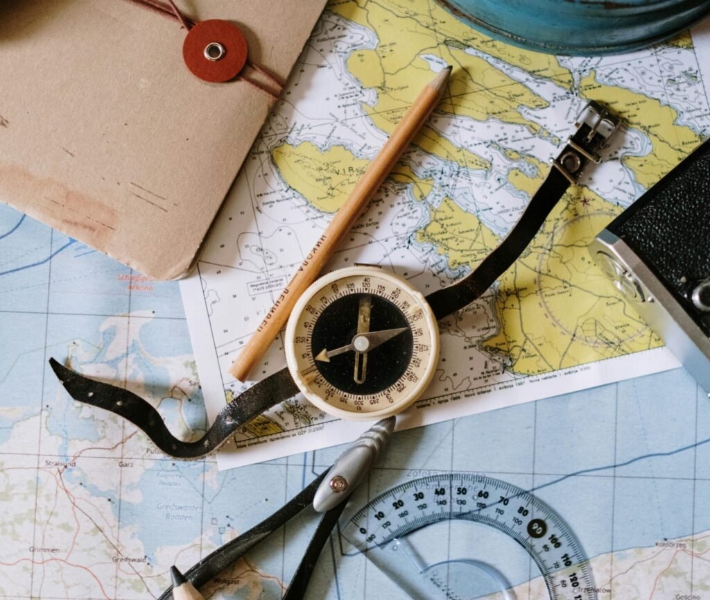 Flat lay of vintage compass, protractor, and maps for navigation study.