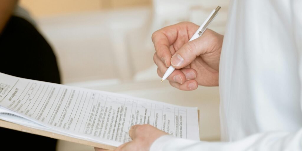 pexels-photo-7088483-7088483 A medical professional in a white coat examines a clipboard with patient documents.