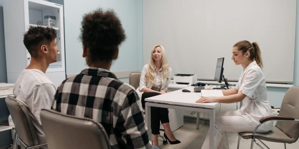 pexels-photo-7108319-7108319 Doctors talking with patients during a medical appointment in a clinic office setting.